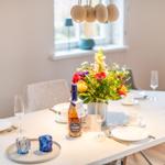 Tisch gedeckt mit Blumen, Gläsern und einer Flasche.