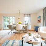 Wohn- und Essbereich mit Holzboden, Tisch, Stühlen und Fenstern.