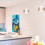 Küche mit moderner Ausstattung und Wandbild mit Fischmotiv.