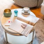 Runder Tisch mit Kaffee, Buch und Dekorationsgegenständen.