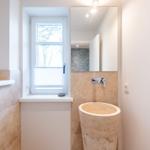 Badezimmer mit Steinwaschbecken, Fenster und Spiegel