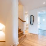 Eingangsbereich mit Holztreppe und Spiegel an der Wand.