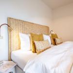 Schlafzimmer mit Bett, Kissen und Wandlampen.