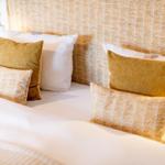 Bettkopfteil mit Muster, weiße Bettwäsche und gelbe Kissen