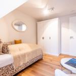 Schlafzimmer mit Bett, Kleiderschrank und runden Tisch.