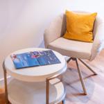 Ein Stuhl mit Kissen und Tisch mit Broschüre.