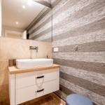 Badezimmer mit Waschbecken, Spiegel und Holzwand