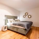 Schlafzimmer mit Bett, Wandspiegeln und Holzboden.