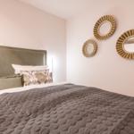 Doppelbett mit Kissen und Wanddekoration aus geflochtenen Runden.