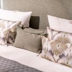 Bettkopfteil mit Kissen in verschiedenen Mustern und Farben