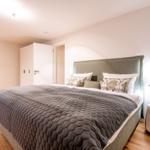 Schlafzimmer mit Bett, Kleiderschrank und Sitzgelegenheit.