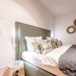 Schlafzimmer mit Bett, Kissen und Wandspiegeln