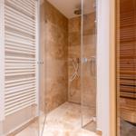 Dusche mit Glaswand, Sauna und Heizkörper an der Wand