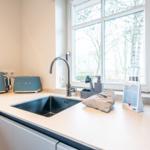 Küche mit Waschbecken, Fenster und Küchengeräten.