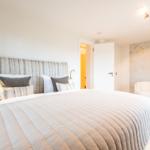 Schlafzimmer mit großem Bett, Wand mit goldener Verzierung und Sitzgelegenheit.