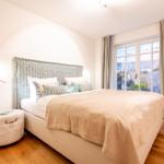 Schlafzimmer mit Blick aufs Meer. Bett, Fenster und Holzboden.