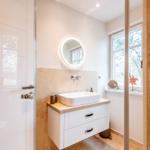 Badezimmer mit Waschbecken, Spiegel und Fenster