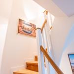 Helle Treppe mit Holzstufen und Bildern an den Wänden.