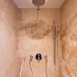Dusche mit Duschbrause, Handbrause und Duschstange an Steinwand