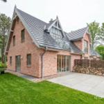 Moderne Backsteinvilla mit großem Garten und Steinmauer.