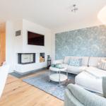 Wohnzimmer mit Sofa, Kamin und Wellenwandtapete.