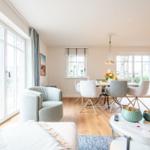 Wohn- und Essbereich mit Holzboden, großen Fenstern und moderner Einrichtung.