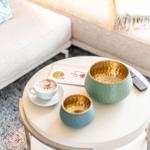 Runde Tisch mit Kaffee, Schale und Fernbedienung vor Sofa