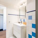 Badezimmer mit Dusche, Waschbecken und blau-weißen Fliesen