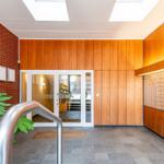 Hauseingang mit Holzwand, Briefkastenreihe und Glasfronttür.