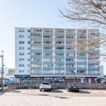 Hochhaus mit Balkonen und Parkplatz vorne