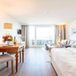 Ein Schlafzimmer mit Schlafcouch, Esstisch und Balkonansicht.