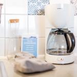 Küchenzeile mit Kaffeemaschine, Wasserglas und Informationskarte.