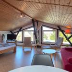 Schlafzimmer mit Doppelbett, Sofa und großem Fenster. Holzdecke und Parkettboden.