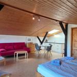 Doppelbett, Sofa, Tisch und Stühle in einem Raum mit Holzdecke und Balken.