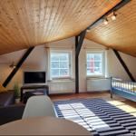 Ein Schlafzimmer mit Dachschrägen, Bett, Sofa und Fernseher.