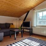 Wohnzimmer mit Sofa, Fernseher und Holzdecke.
