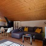 Wohnbereich mit Sofa, Tisch und Küchenzeile unter Holzdecke.