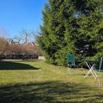 Garten mit Strandkorb, Tisch und Stühlen, Grasfläche und Bäumen.