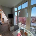 Schlafzimmer mit Balkon und TV. Große Fenster bieten Blick auf die Stadt.