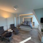 Schlafzimmer mit Bett, Sessel, Fernseher und Holzboden.