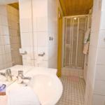 Bad mit Waschbecken, Spiegel und Dusche mit Glaswand.