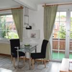 Esszimmer mit Tisch, zwei Stühlen, Fenstern und Balkontür.