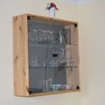 Holzregal mit Glasfront enthält Gläser und Tassen