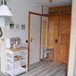 Küche mit Holzregal und Tür zum Schlafzimmer. Küchenzeile mit blauen Schränken.