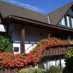 Haus mit Blumen und Schild für Gästezimmer und Ferienwohnungen.