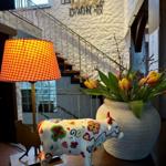 Tisch mit dekorativer Kuh, Blumen und Lampe vor Treppenhaus