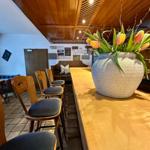 Holzbar mit Stühlen und Blumenarrangement im Raum