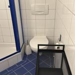 Badezimmer mit Toilette, Dusche und schwarzer Ablage