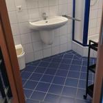 Badezimmer mit blau gefliestem Boden, Waschbecken und Dusche.