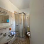 Badezimmer mit Dusche, Waschbecken und Toilette.